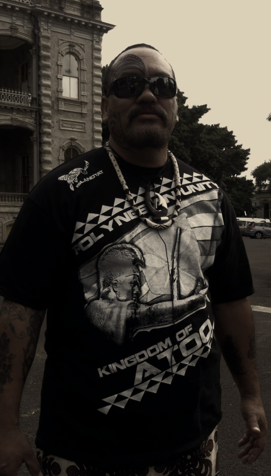 The Ali'i Nui standing before 'Iolani Palace, facial moko partially completed